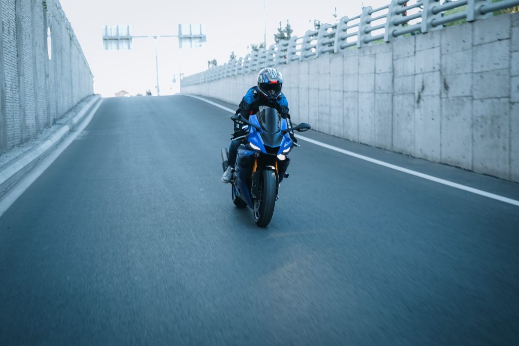 Motociclist cu cască pe un drum urban, imagine pentru pregătirea examenului moto A1, A2 și A.